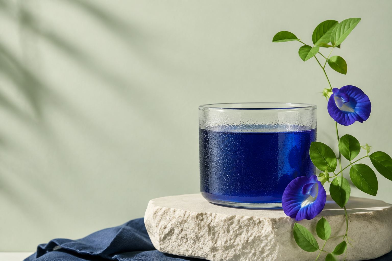 Blue butterfly pea tea beside butterfly pea flowers