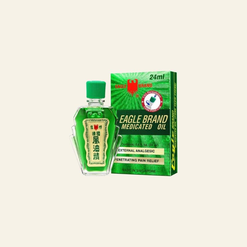 Eagle Brand Medicated Oil 24 ml green-label bottle and box on a warm cream background