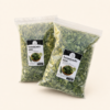 Two 100 g bags of dried pandan leaves on a plain ivory background