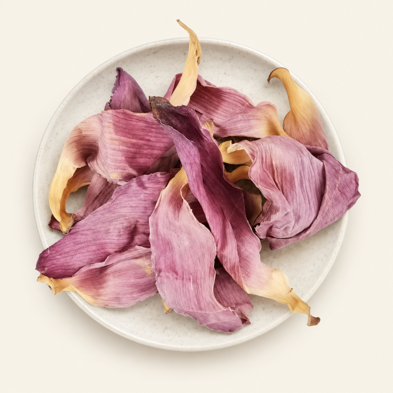 Dried pink lotus petals in a shallow plate on a warm cream background