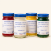Red, white, yellow and green Wat Pho Otsathip balm jars on a warm cream background