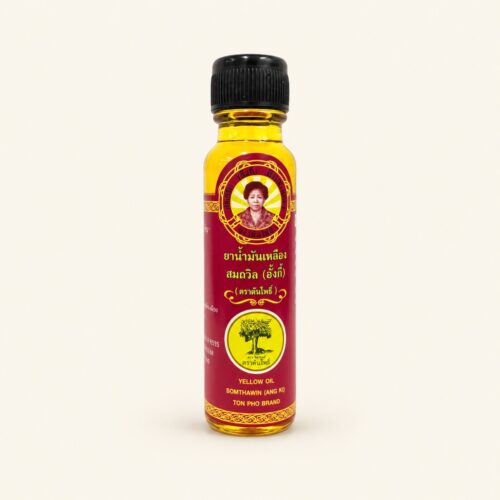 Somthawin Ang Ki yellow herbal oil 24 ml bottle on a warm cream background